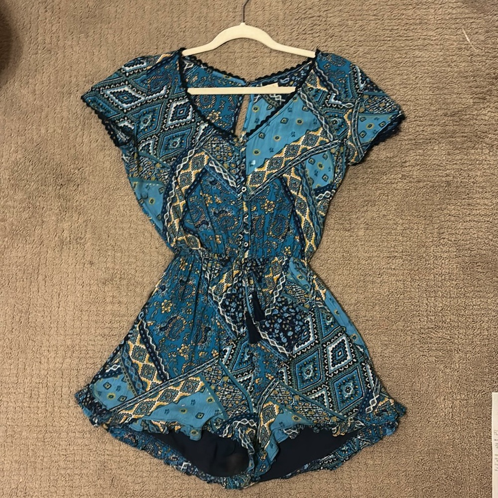 This romper is navy, blue, & gold. It has buttons and an elastic waist band.